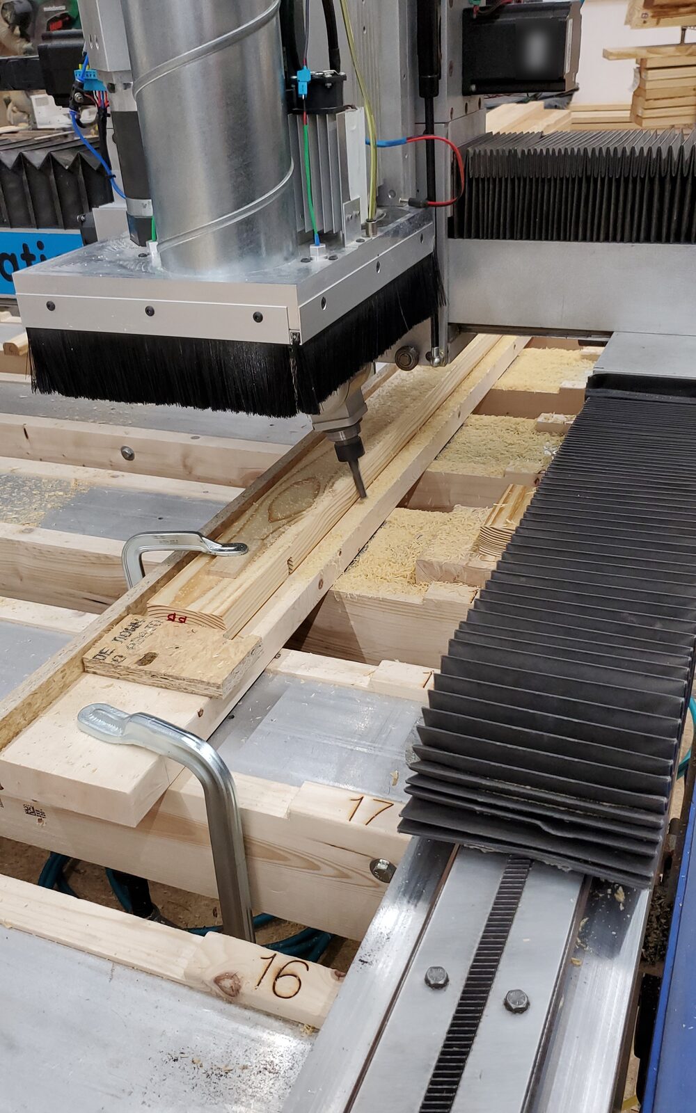 Angle head milling a wooden dome strut held in a clamping jig on the CNC router, with numbered strut parts 16 and 17