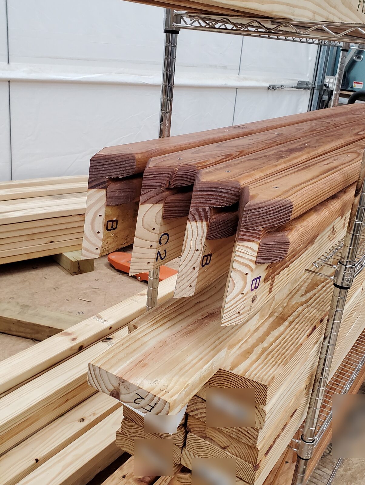 Finished dome-house struts with compound-mitered, labeled ends, racked and ready for assembly